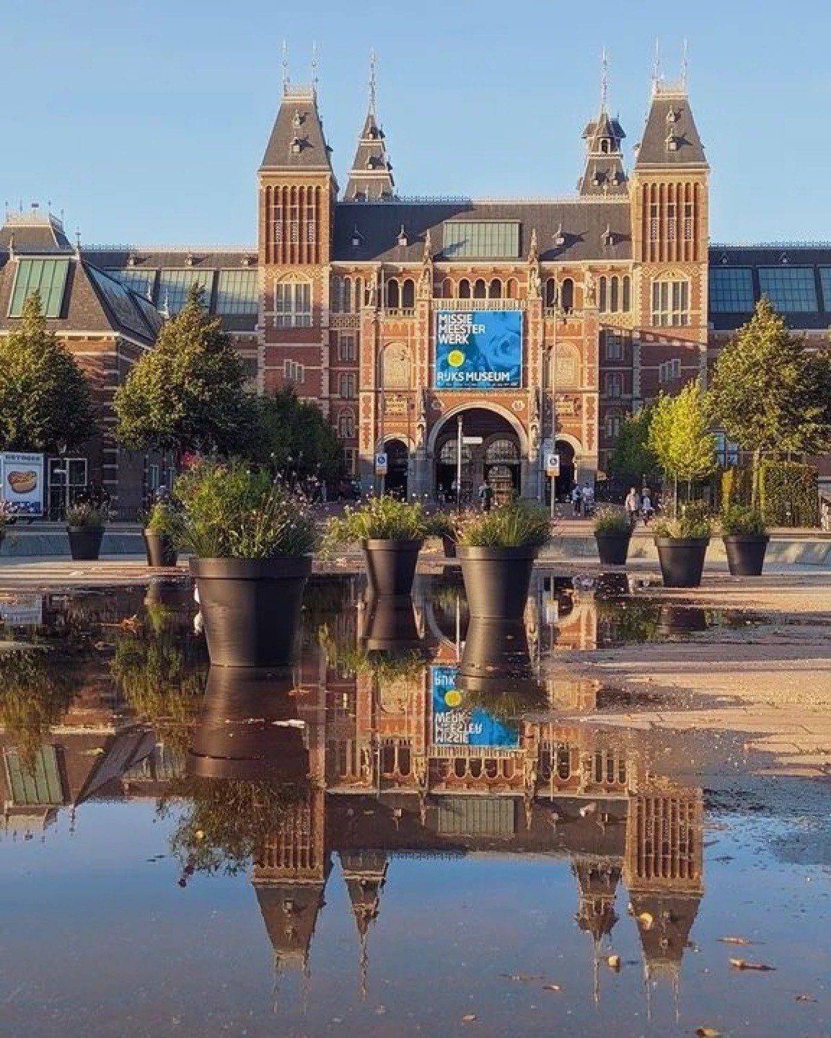 The Rijksmuseum façade reflected in the water at Museumplein.