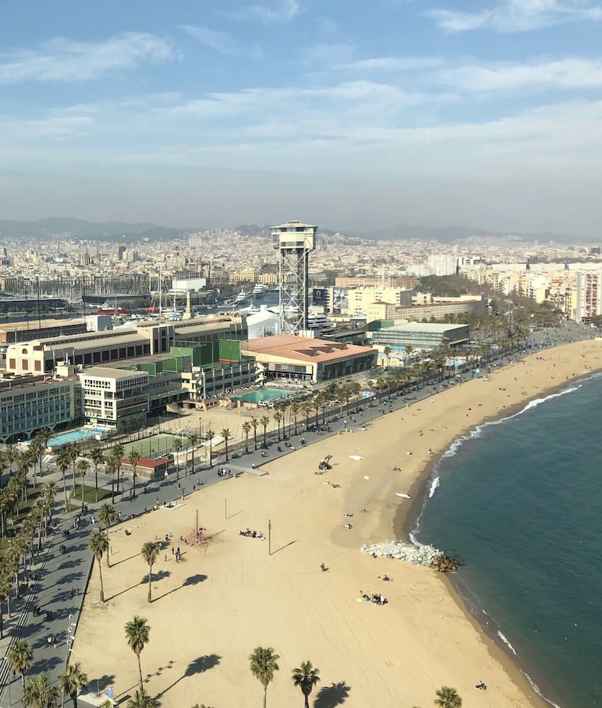 Barceloneta beach, its promenade and waterfront buildings seen from above.