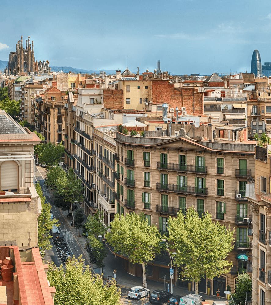 Housing blocks, tree-lined streets and rooftops near the Sagrada Família, with the basilica in the distance.