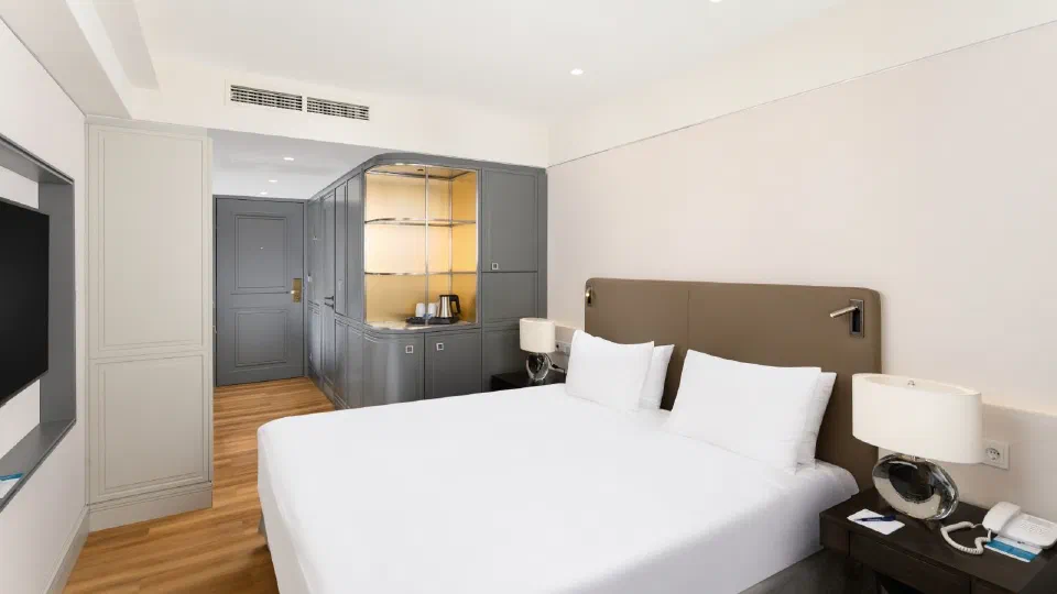 Double bed and grey fitted cabinetry in a renovated Astoria Superior room.