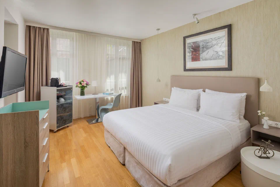 Double bed, wooden floor and a desk beside the window in a Casati guest room.