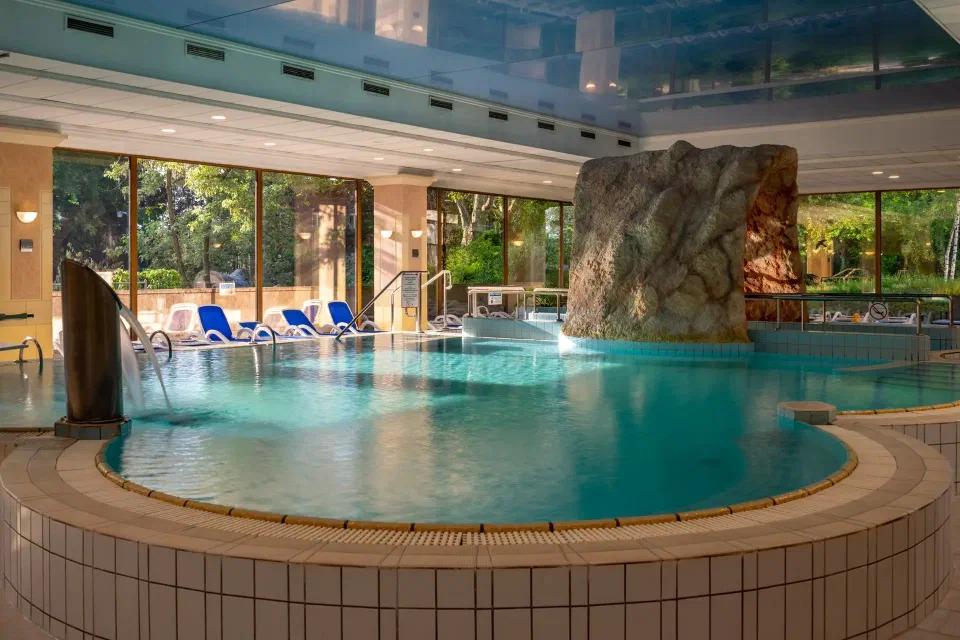 Indoor spa pool with curved edges and garden-facing windows at Ensana Thermal Margaret Island.