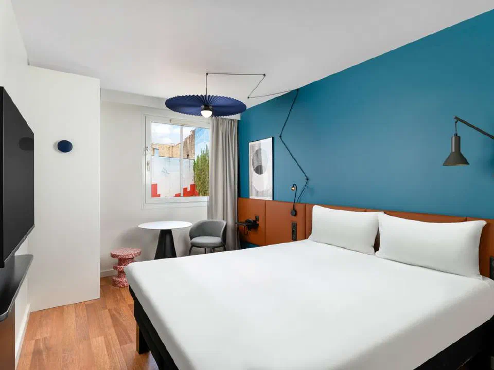 Double bed with an orange headboard and blue wall at ibis Budapest Centrum.