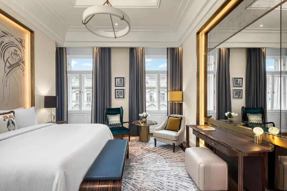 Bed, high ceiling and tall window in a Matild Palace Deluxe guest room.