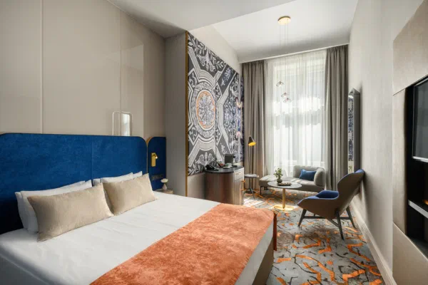 Blue headboard, patterned artwork and a window-side chair in a Hotel Moments Signature Design room.