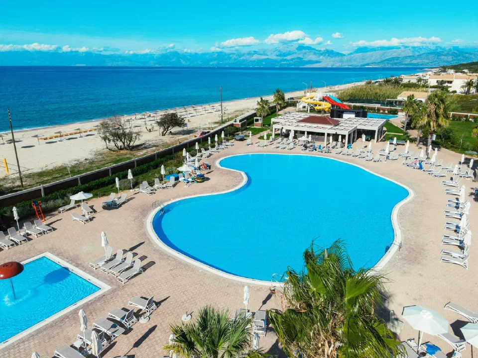 Almyros Beach Resort’s outdoor pool and sun terrace beside the sandy shore.
