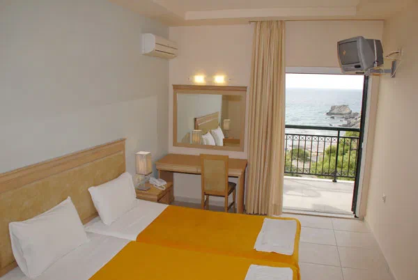 Twin beds and a balcony facing the sea in a promotional room photo from Glyfada Beach Hotel.