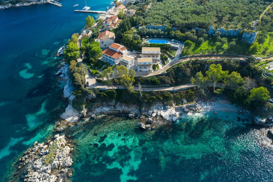 An aerial view of Kassiopi Bay’s apartment buildings and pool above the rocky coves.