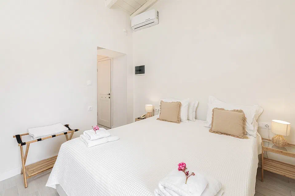 The double bed, bedside lamps and folded towels in a Classic Double Cosy room at Zefiros.