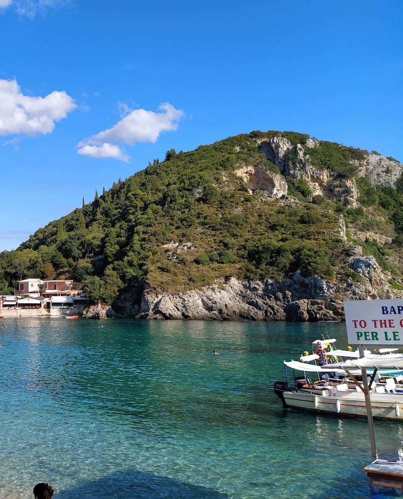The main Paleokastritsa bay with boats below a wooded headland.