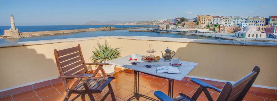 Breakfast table and chairs on a terrace overlooking Chania harbour.