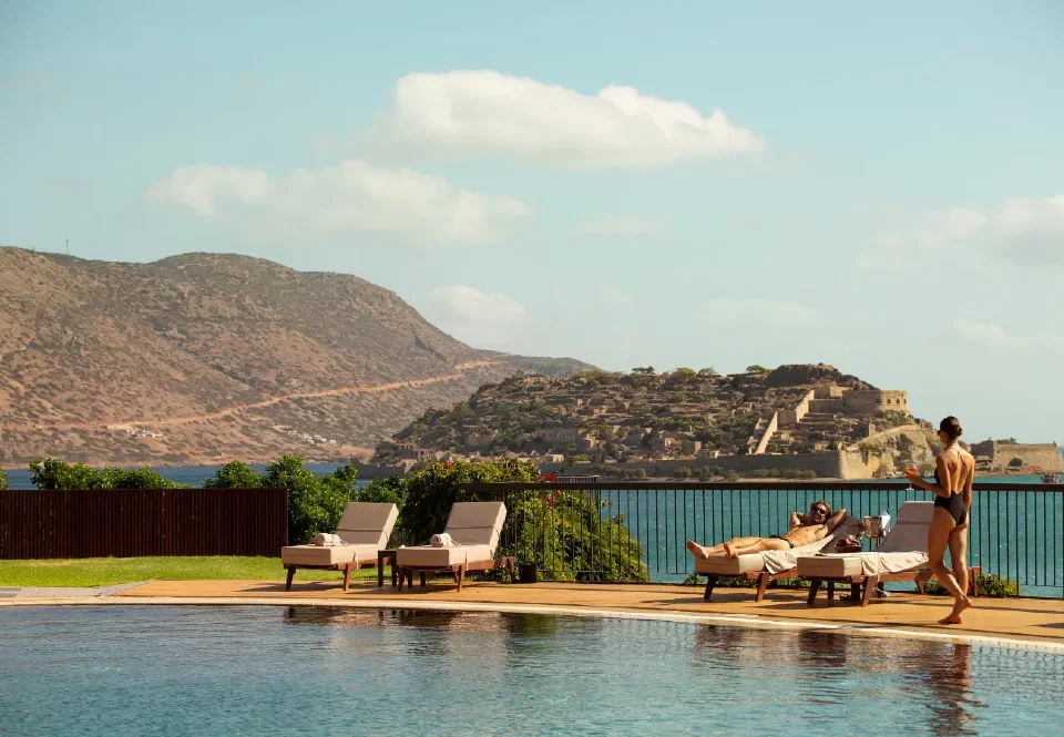 Shared pool and loungers at Domes of Elounda, with Spinalonga across the water.