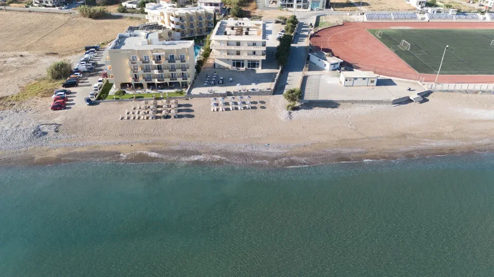 Aerial view of Galini Beach Hotel buildings, parasols and the shoreline in Kissamos.
