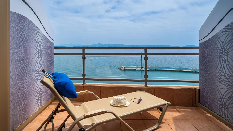 A sea-view balcony with a lounger and small table at Minos Boutique Hotel.