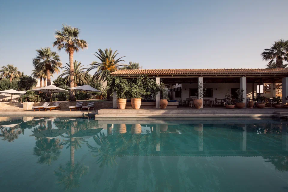 A palm-lined pool and low resort buildings at Phāea Cretan Malia.