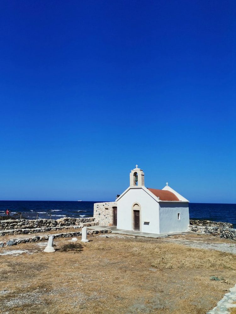 A small white coastal chapel beside archaeological remains at Hersonissos.