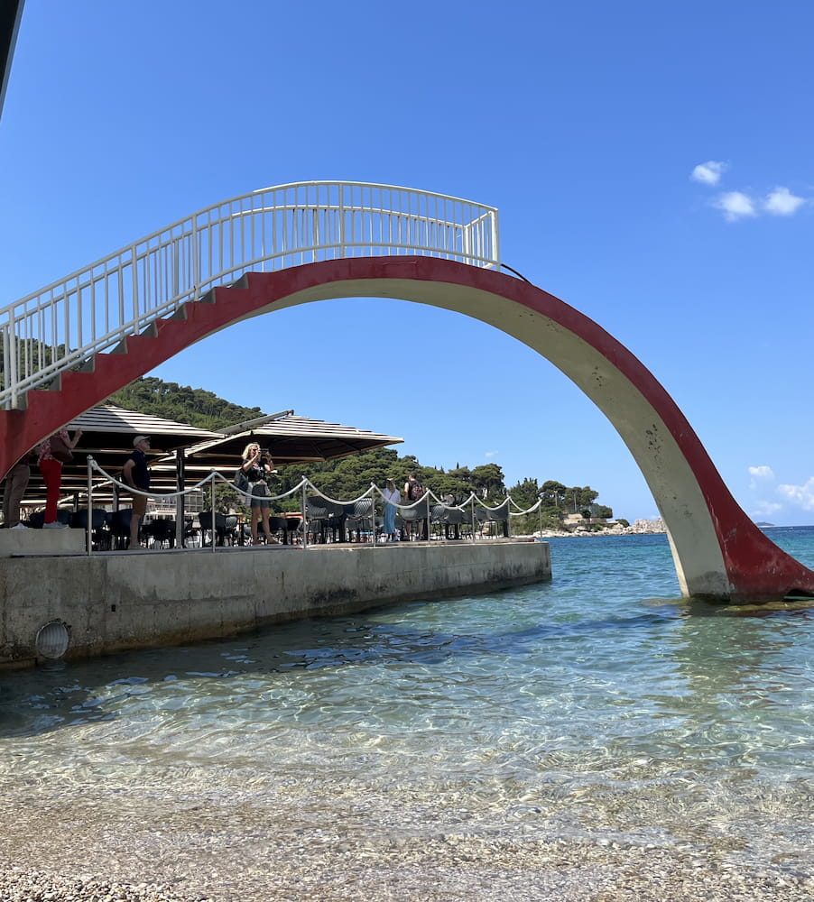 An arch on the promenade around Lapad Bay, with the beach behind it.