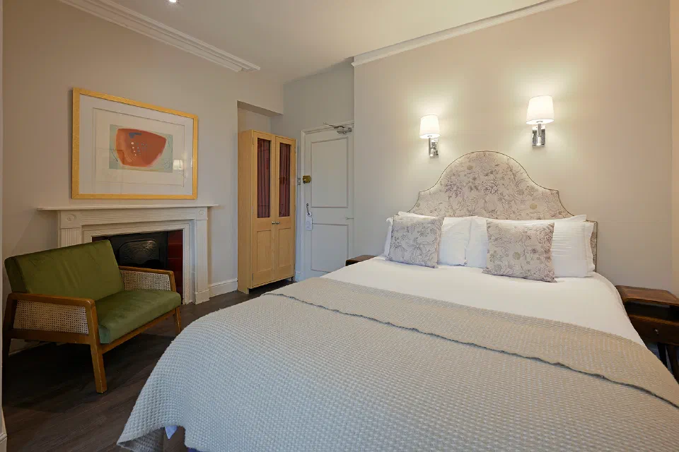 Superior Double room at Harlingford Hotel with a floral headboard, fireplace and green armchair