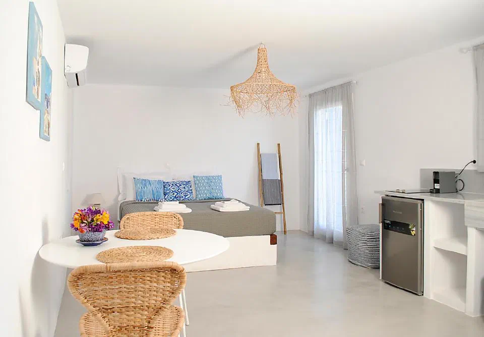 Bed, round dining table, refrigerator and counter in a Sunrise View Lefkes apartment.