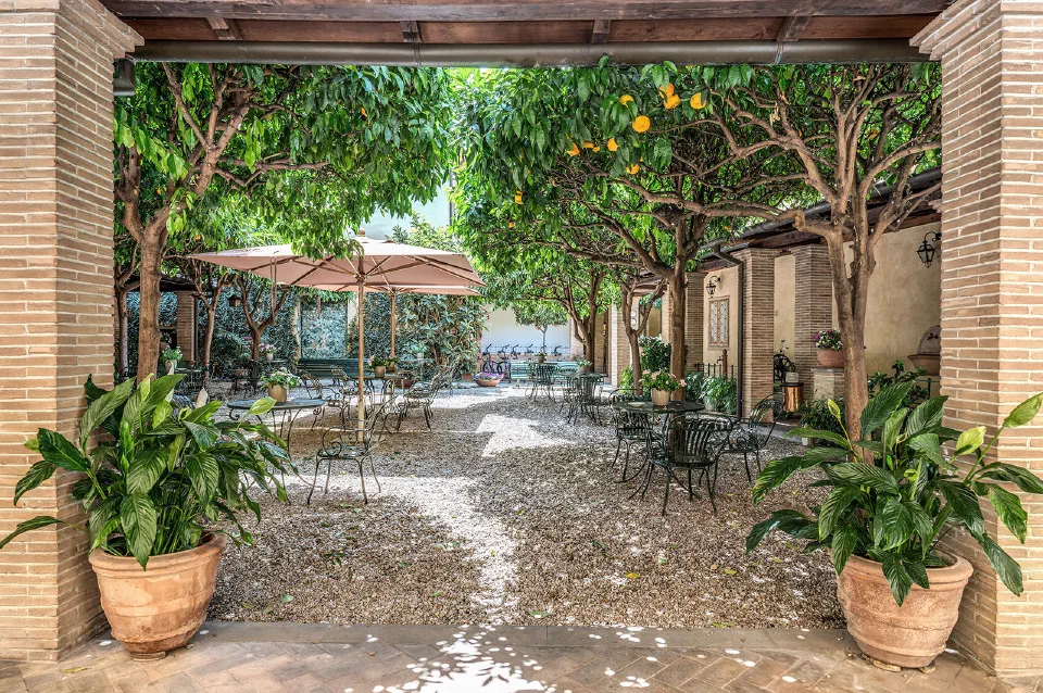 Orange trees shade café tables in the shared courtyard garden at Hotel Santa Maria in Trastevere.
