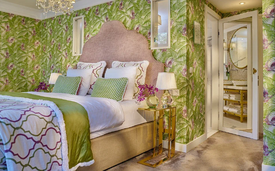 A richly decorated Canal Room at Hotel Estheréa, with green floral walls and a pink upholstered headboard.