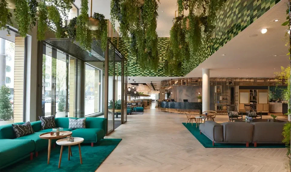 Botanical lobby lounge at Hyatt Regency Amsterdam, with hanging greenery and teal seating.