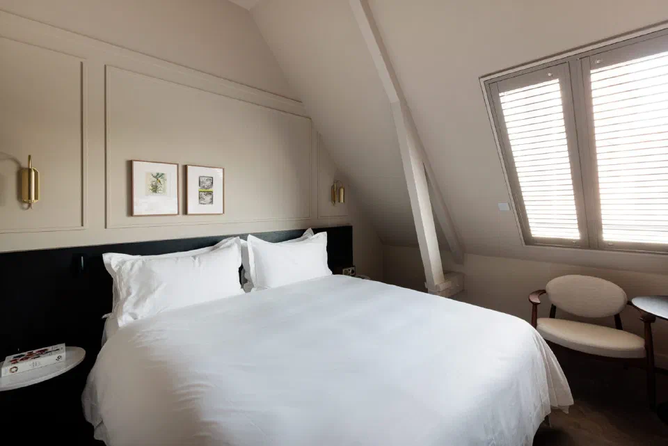 A cream-toned Luxury Room at Pillows Maurits at the Park, with a double bed and shuttered window.
