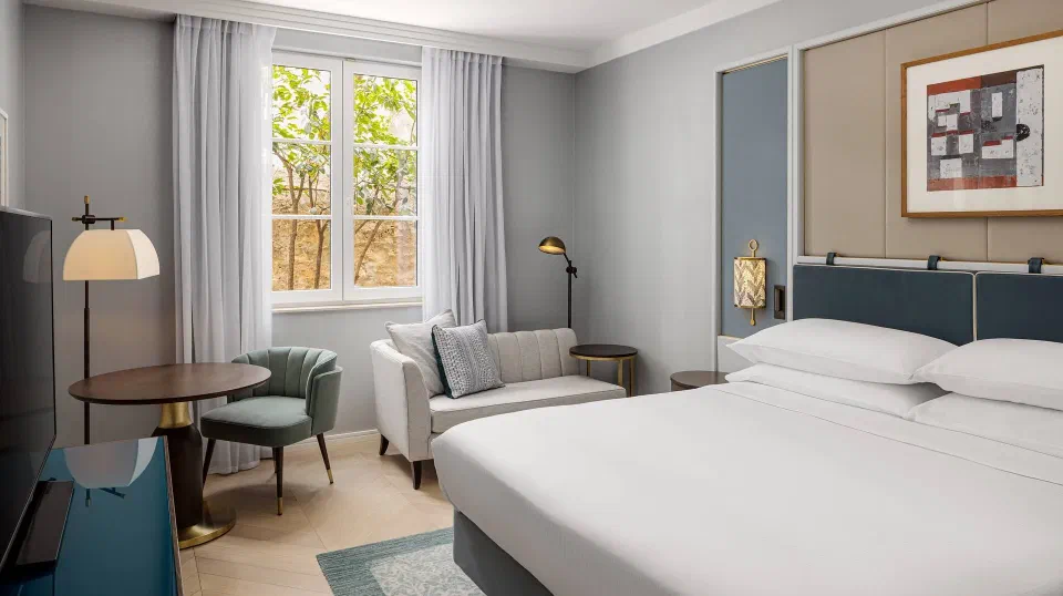 Guest room with a bed, sofa and window at Hilton Imperial Dubrovnik.