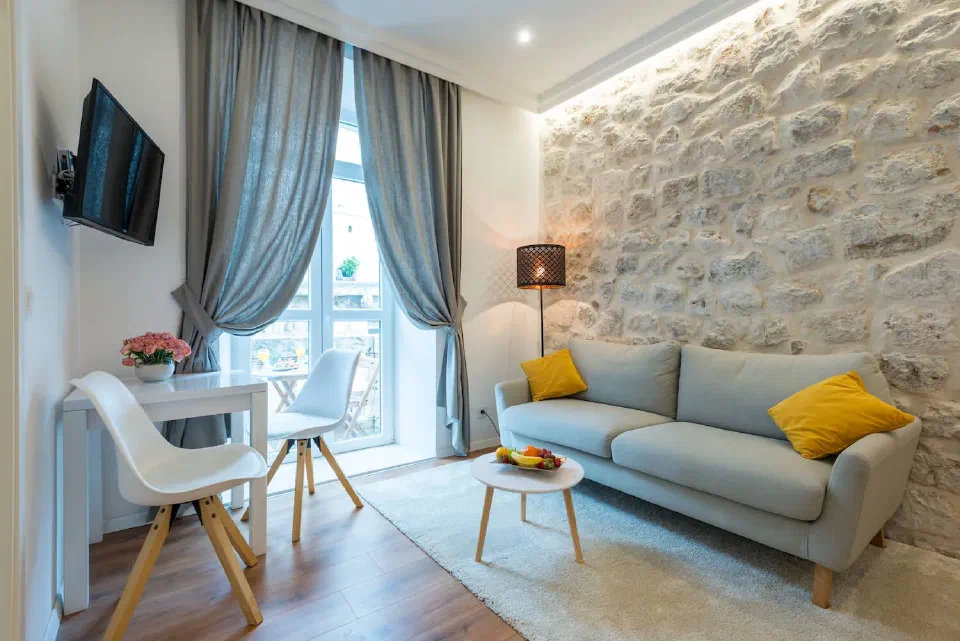 Dining table and sitting area beside exposed stone walls in a Deluxe Suite with Balcony at Scalini Palace.