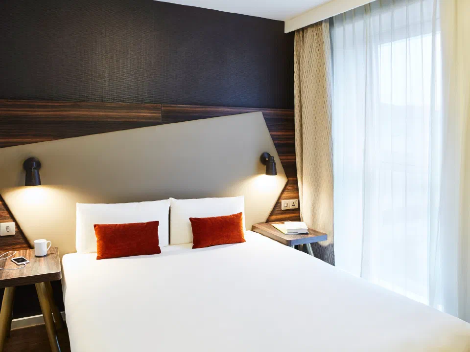 Bedroom with a double bed, red cushions and a tall window at Adagio Edinburgh Royal Mile.