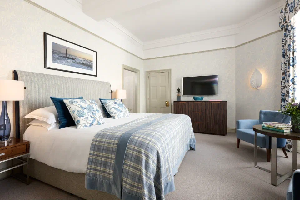 Blue-and-cream Deluxe Room with a tartan bedcover and armchair at The Balmoral.