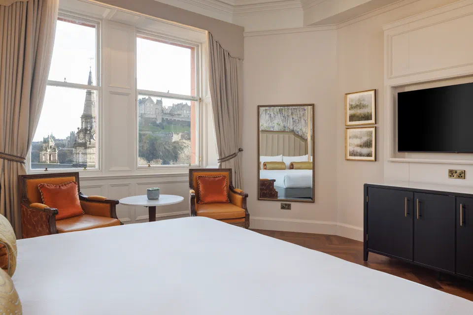 Room at The Caledonian with orange armchairs and Edinburgh Castle visible through the window.