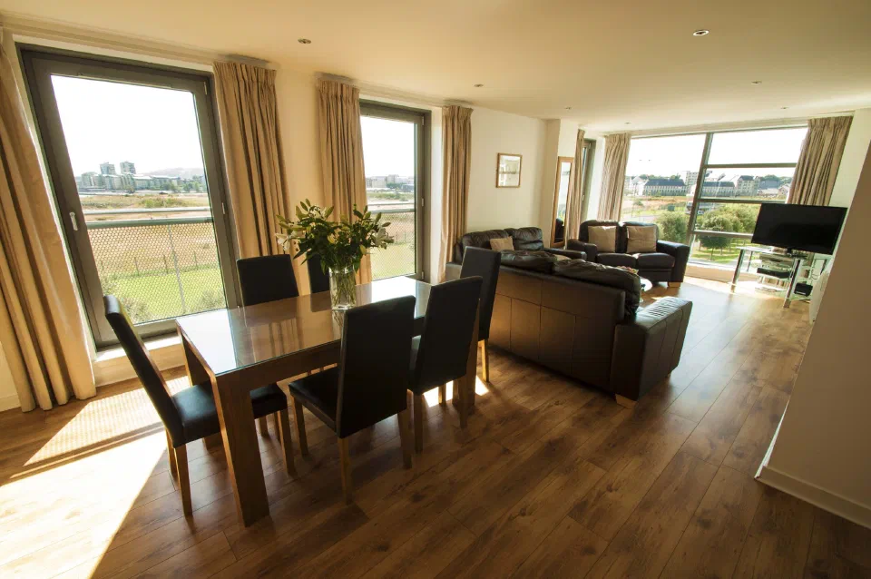 Dining table, leather sofas and large windows in a Family Apartment at Ocean Serviced Apartments.