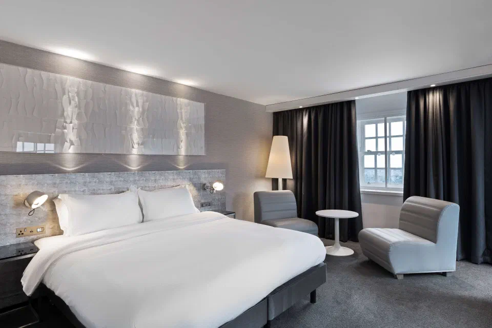 Double bed and two grey chairs in a Superior room at Radisson Blu Edinburgh.