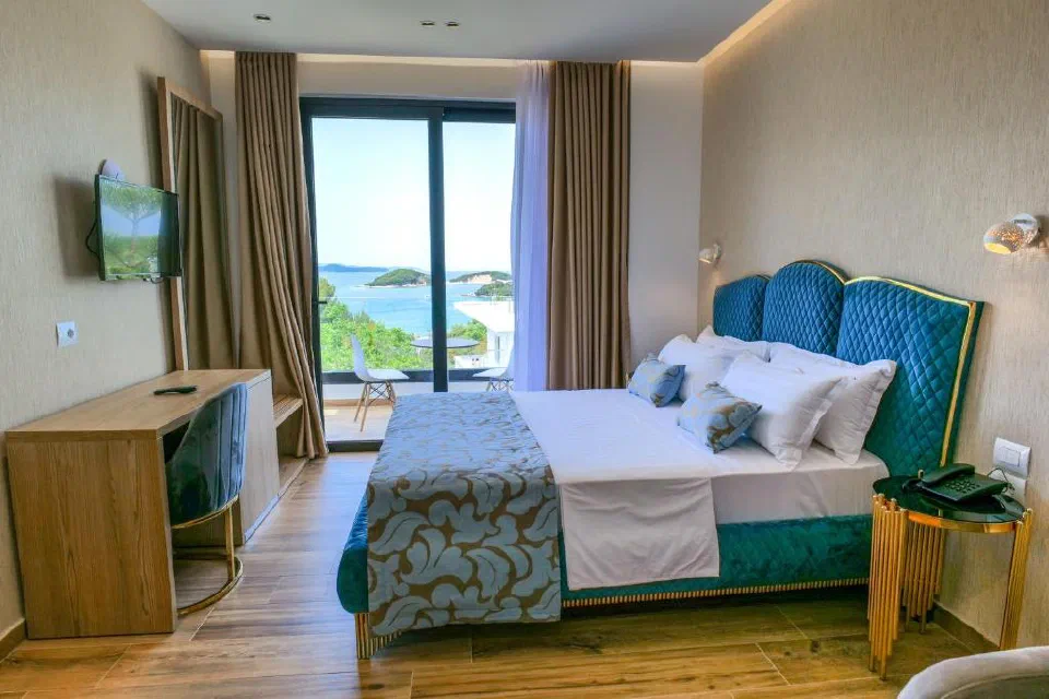 Bora Bora Hotel room with a blue bed and balcony glazing framing the sea and islands.
