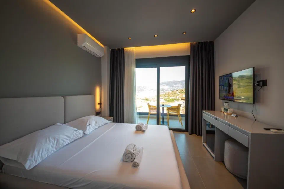A Lake View double room with bed, balcony and the lagoon and hills beyond.