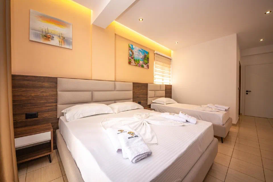 Bright Hotel New Crystal guest room with two beds, wood paneling and folded towels.