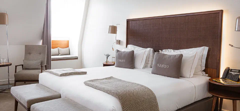 Superior bedroom at Corpo Santo, with window-side seating and upholstered stools.