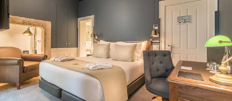 Classic Interior bedroom at Hotel da Baixa, with an armchair and desk.