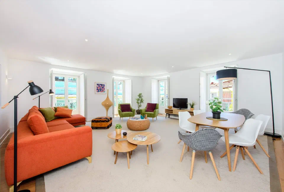 Apartment living room at Martinhal Chiado, with orange sofa and dining space.