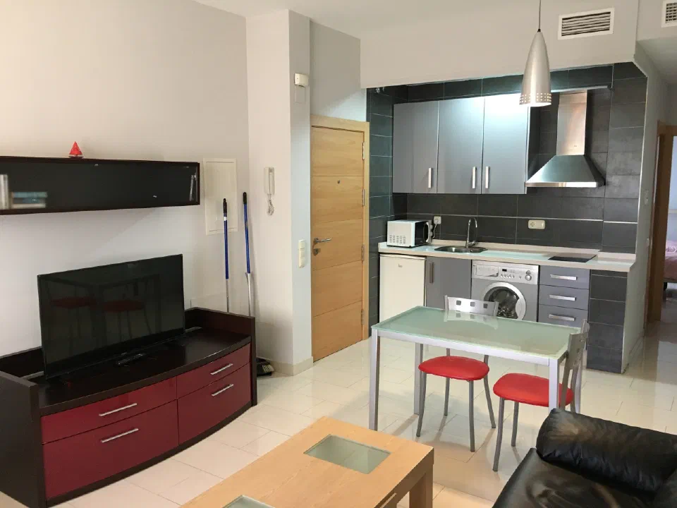 Kitchen, washing machine and dining table in the ground-floor unit at Apartamentos El Palo