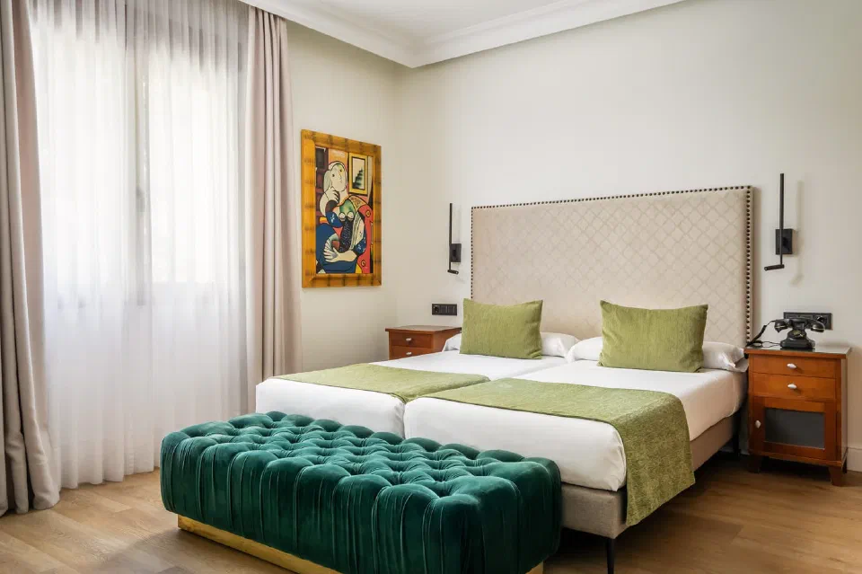 A bed with green cushions and a teal bench in a Superior room at BYPILLOW California.