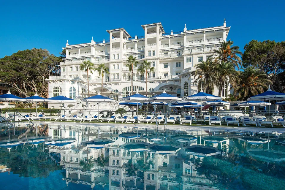 Outdoor pool, sun loungers and the white façade of Gran Hotel Miramar in Málaga