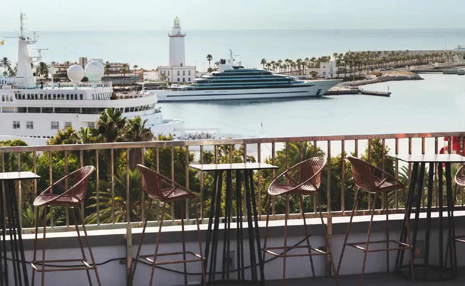 Chairs on the shared rooftop terrace at Catalonia Molina Lario, overlooking Málaga harbour and La Farola.