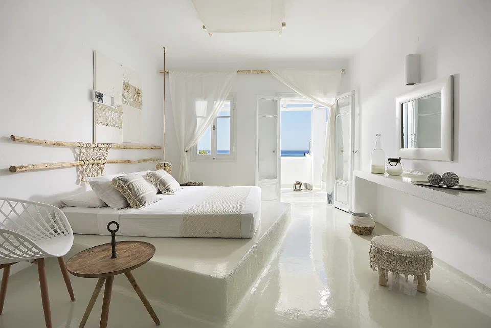 White double bedroom with gauzy curtains and an open sea-facing doorway at Artemis Seaside Resort.
