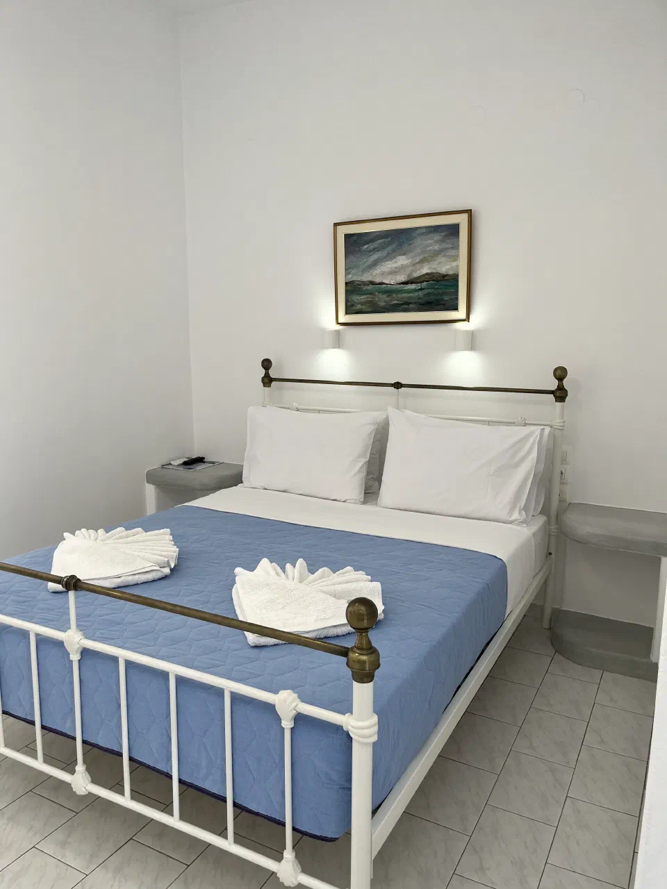 Bright double-bed guest room with blue bedding and white walls at Captain Stavros.