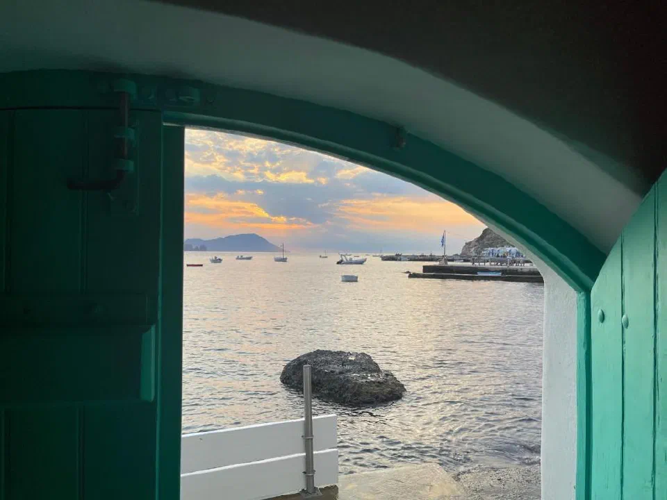View through White Coral’s turquoise boathouse doorway towards the waterfront at dusk.