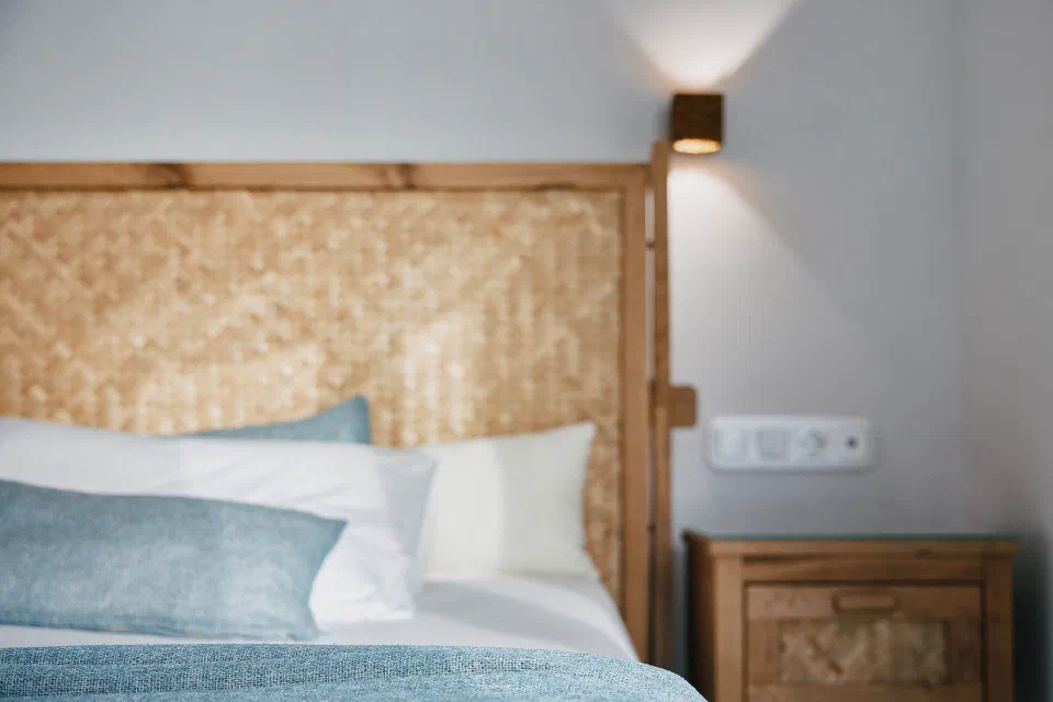 Kalergis Studios guest bed with blue and white pillows and a woven wooden headboard.