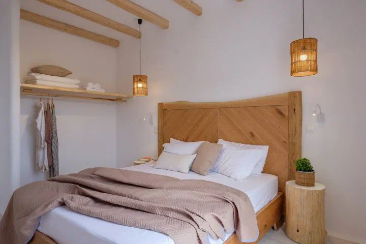 Orkos Beach Hotel Triple Room with a wooden headboard, double bed and hanging lamps.