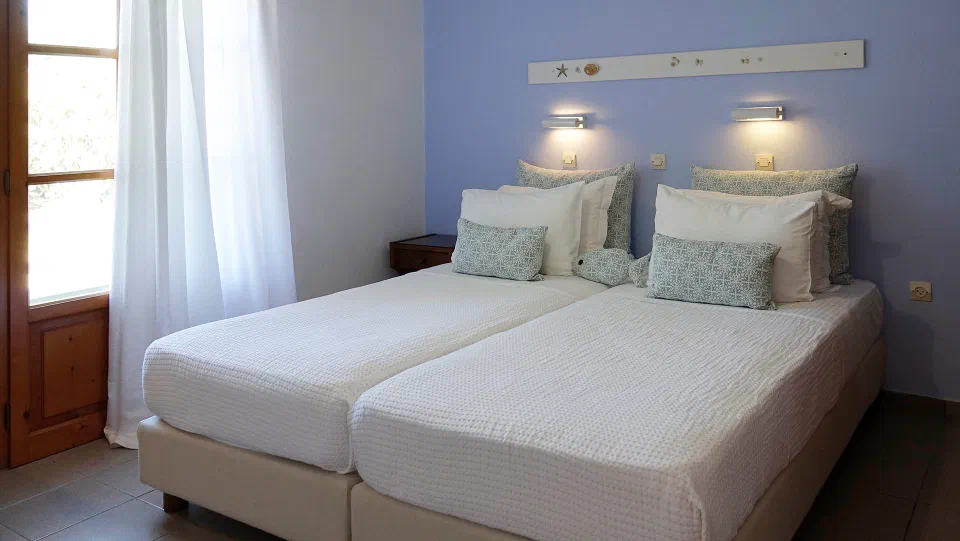 One bedroom in Elena’s two-bedroom apartment, with a blue wall and balcony doors